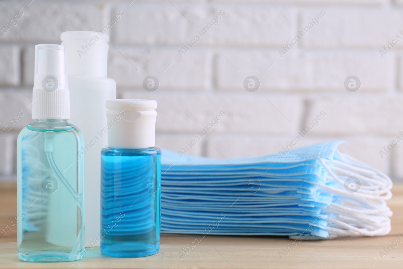 Photo of Hand sanitizers and respiratory masks on wooden table. Protective essentials during COVID-19 pandemic