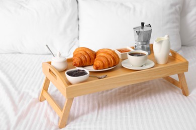 Photo of Wooden tray with tasty breakfast on bed
