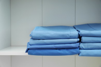 Photo of Light blue medical uniforms on white rack