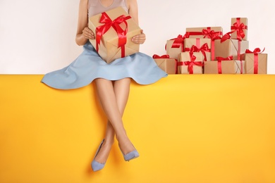 Photo of Woman with gift boxes sitting on yellow background, closeup. Black Friday
