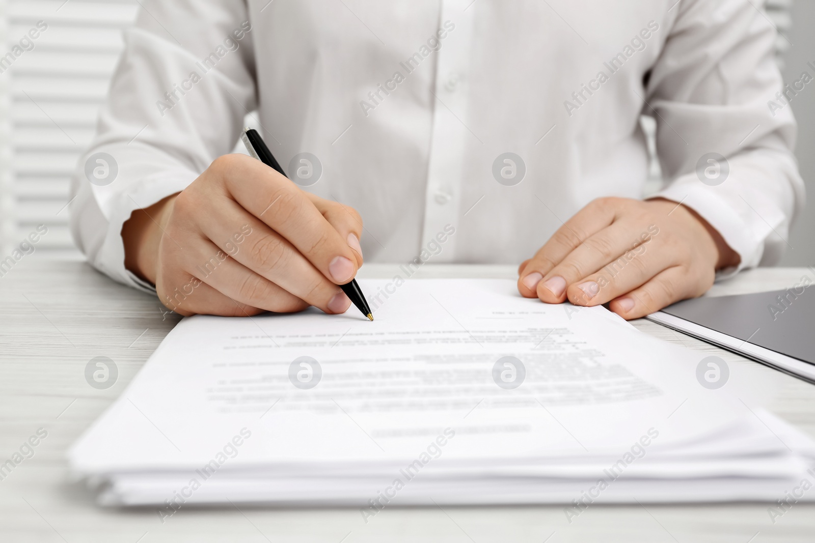 Photo of Man signing document at wooden table, closeup