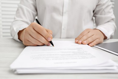 Man signing document at wooden table, closeup
