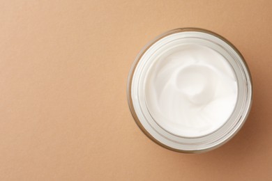 Jar of face cream on beige background, top view. Space for text