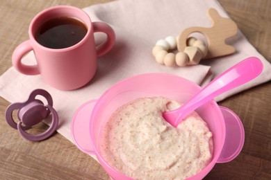 Photo of Baby food. Puree in bowl, drink, toy and soother on wooden table