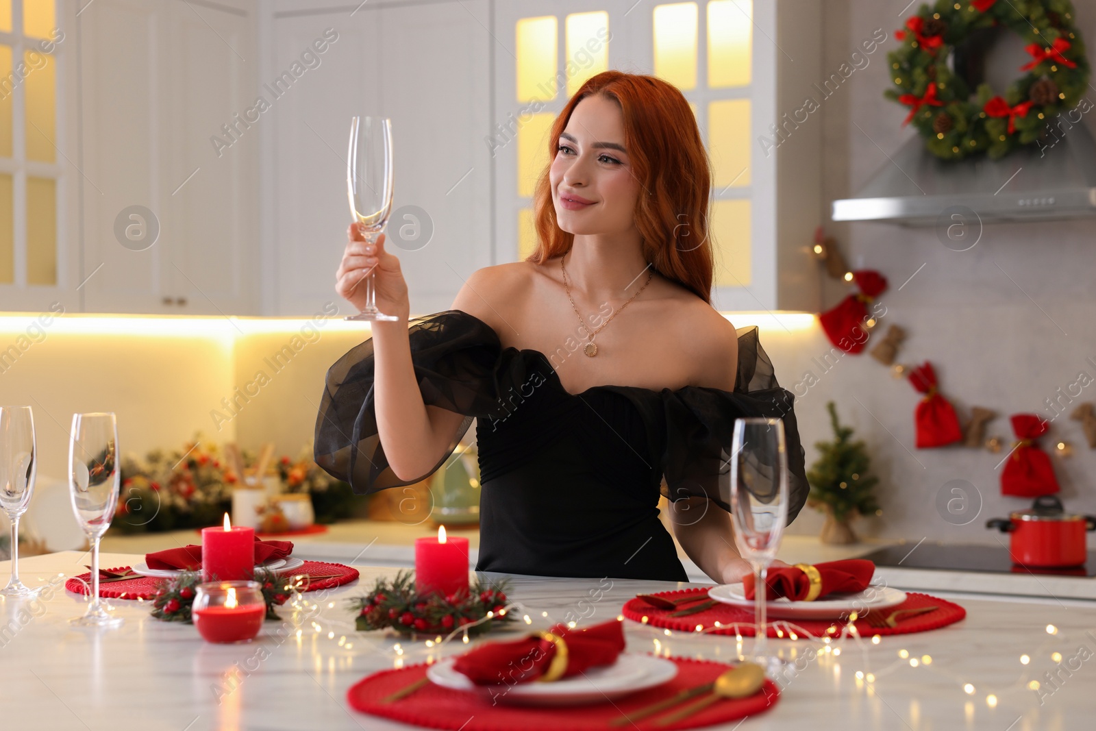 Photo of Beautiful young woman setting table for Christmas celebration in kitchen