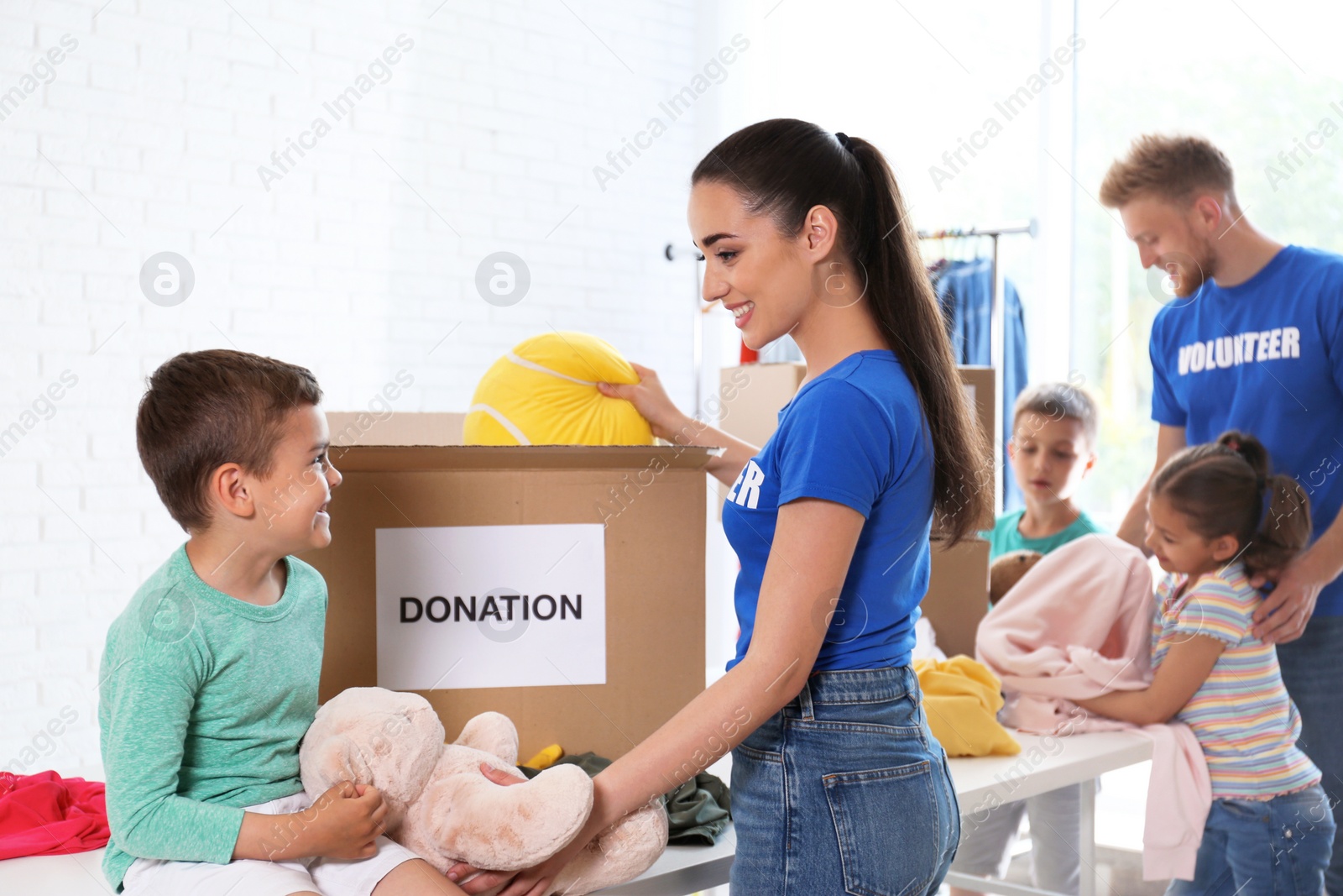 Photo of Volunteers with children sorting donation goods indoors