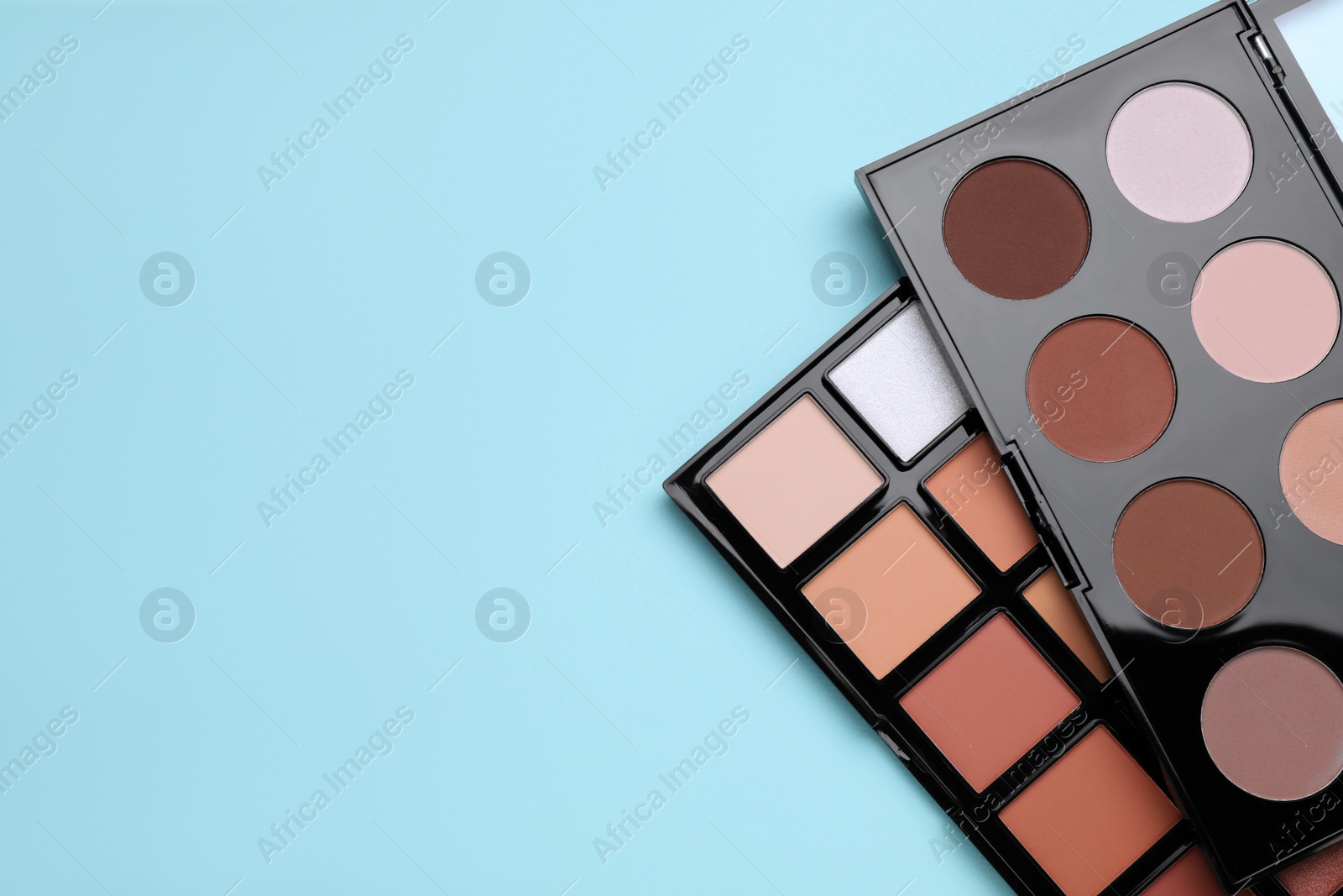 Photo of Colorful contouring palettes on light blue background, top view with space for text. Professional cosmetic product