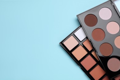 Photo of Colorful contouring palettes on light blue background, top view with space for text. Professional cosmetic product