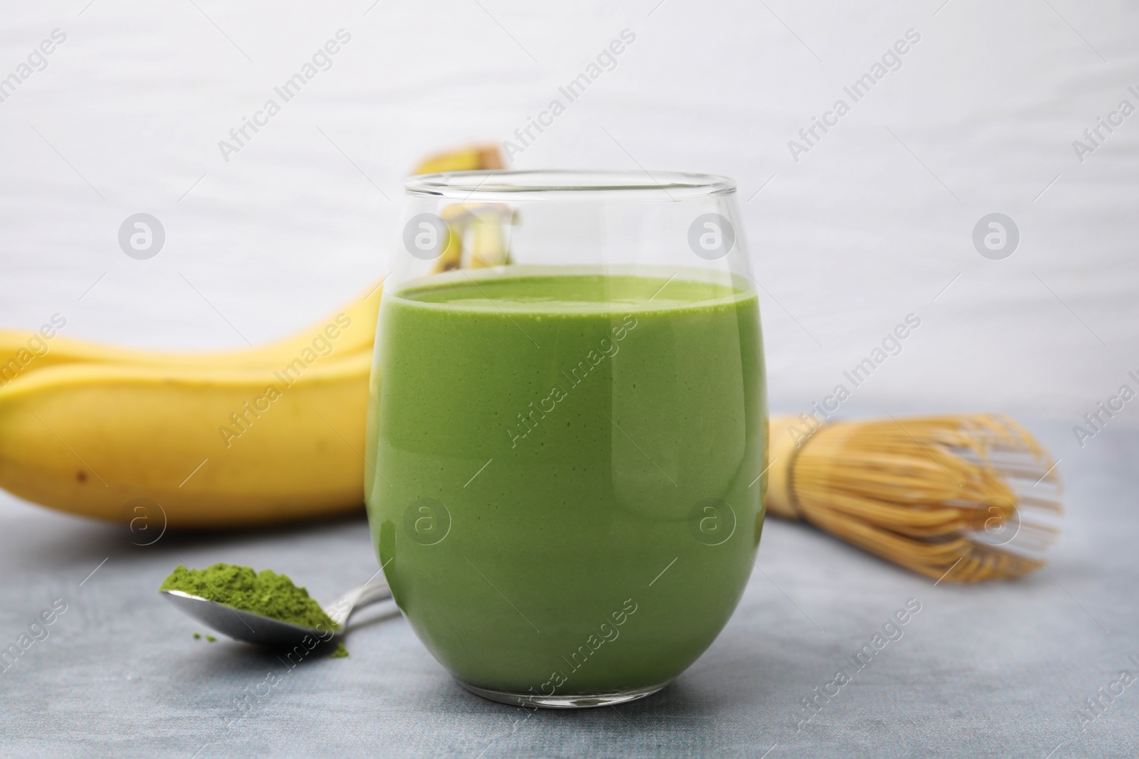 Photo of Glass of tasty matcha smoothie on light grey table