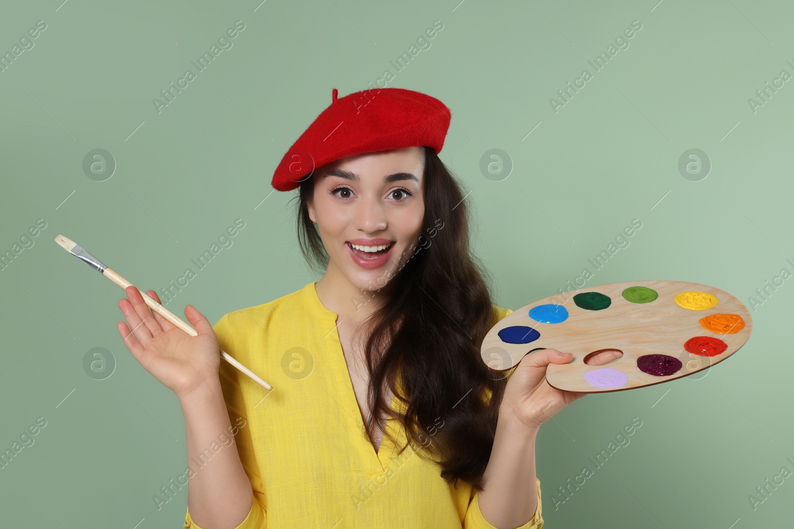 Photo of Woman with painting tools on pale green background. Young artist