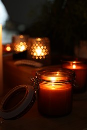 Lit candles on wooden table in dark room. Space for text
