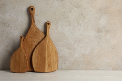 Photo of Wooden cutting boards on white table near textured wall, space for text