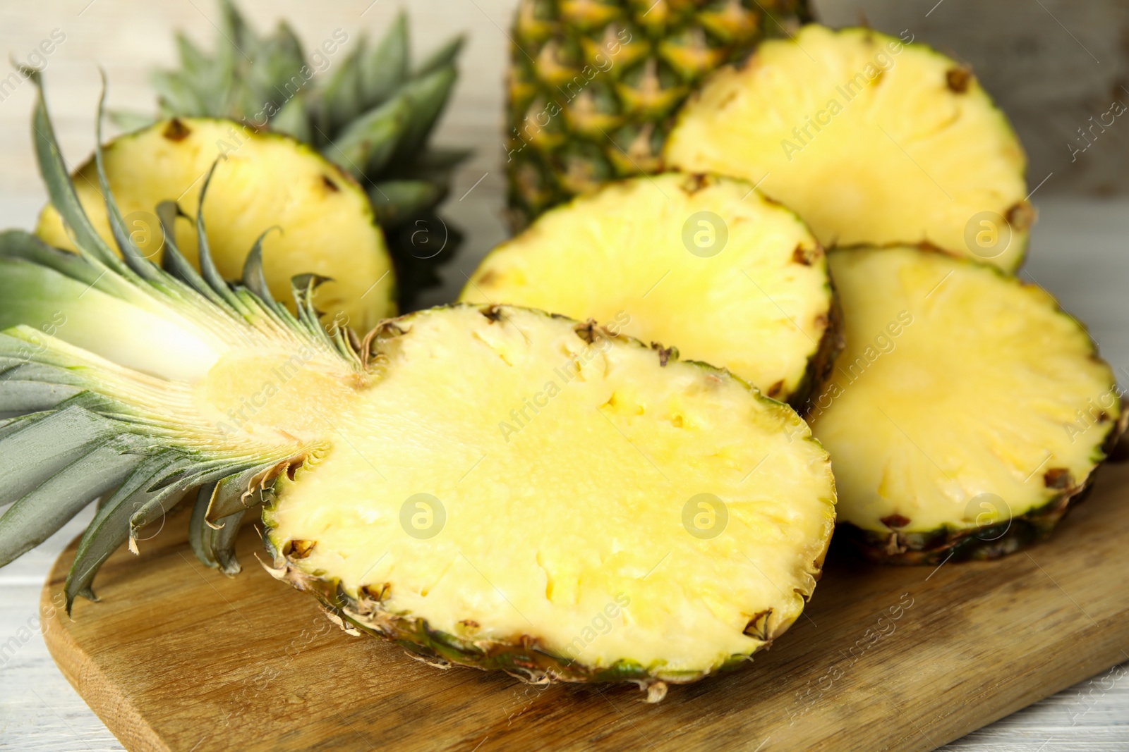 Photo of Slices of fresh pineapple on wooden board, closeup