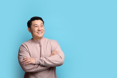 Portrait of happy man on light blue background. Space for text