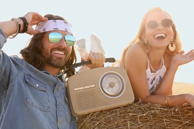 Photo of Happy hippie couple with radio receiver in field