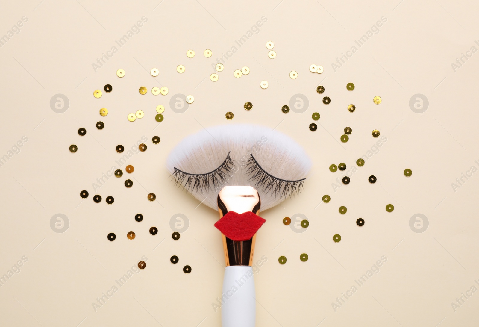 Photo of Makeup brush with false eyelashes and red lips as beautiful face on beige background, flat lay