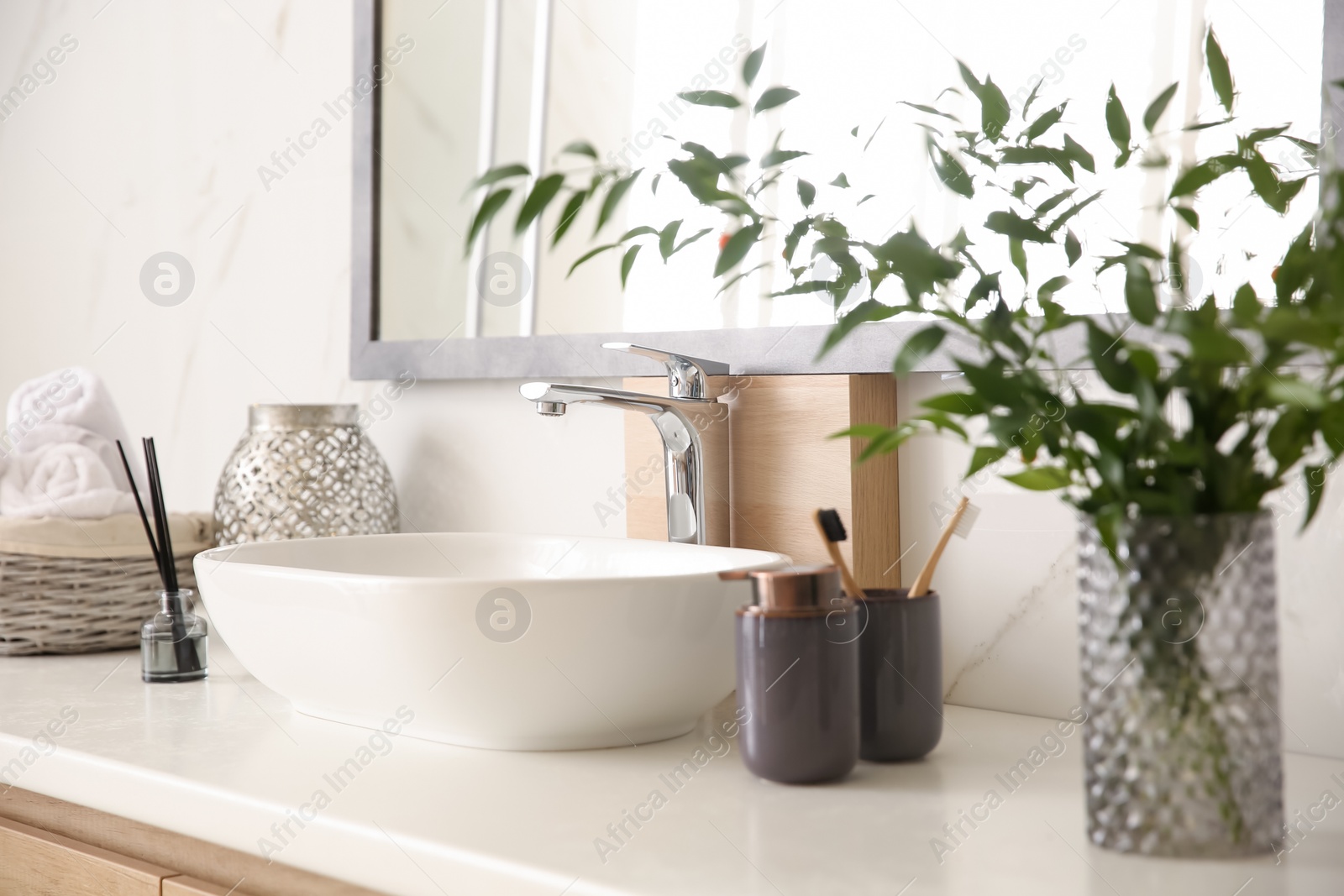 Photo of Vase with beautiful branches and toiletries near vessel sink in bathroom. Interior design