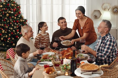 Woman with bowl of traditional Christmas kutia and her family during festive dinner at home. Slavic dish