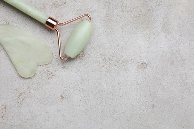 Photo of Gua sha stone and face roller on light table, flat lay. Space for text
