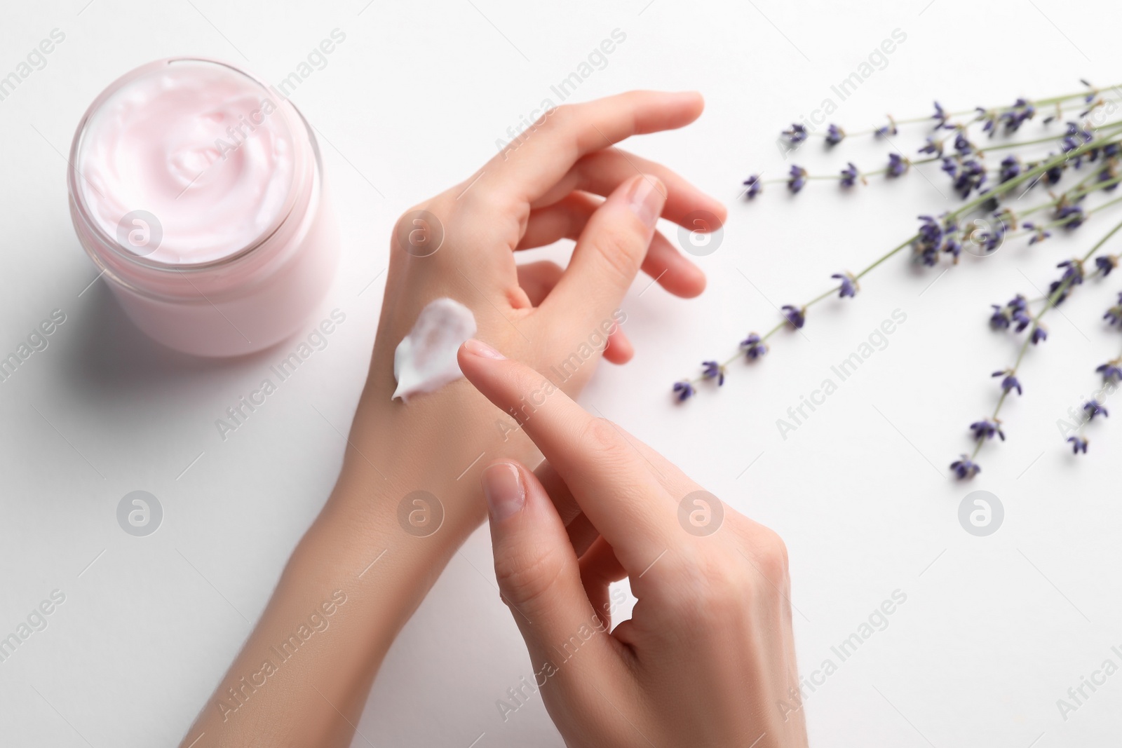 Photo of Woman applying hand cream on white background, top view