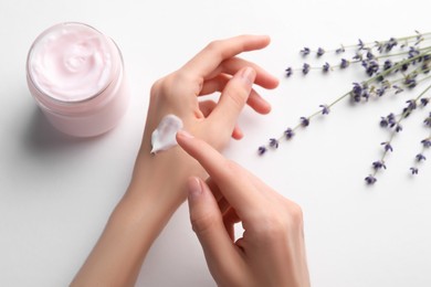 Woman applying hand cream on white background, top view