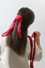 Photo of Young woman with stylish red bandana on light background, back view