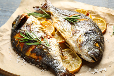 Delicious roasted fish with lemon on parchment paper, closeup