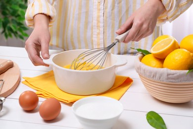 Photo of Woman cooking lemon curd at white wooden table, closeup