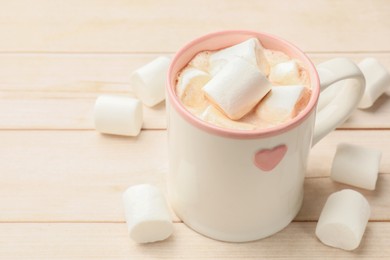 Photo of Tasty hot chocolate with marshmallows on light wooden table, closeup. Space for text