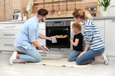 Happy family baking cookies in oven at home