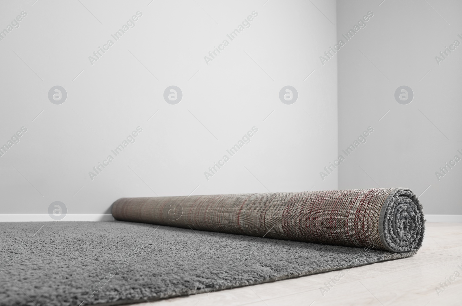 Photo of Rolled grey carpet on floor in room, closeup