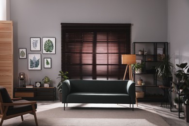Photo of Stylish living room interior with comfortable sofa and green houseplants