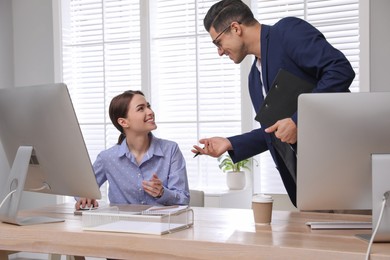 Businessman helping intern with work in office