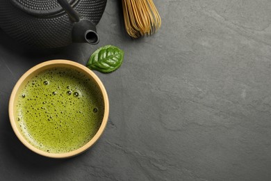 Photo of Cup of fresh matcha tea and leaf on black table, flat lay. Space for text