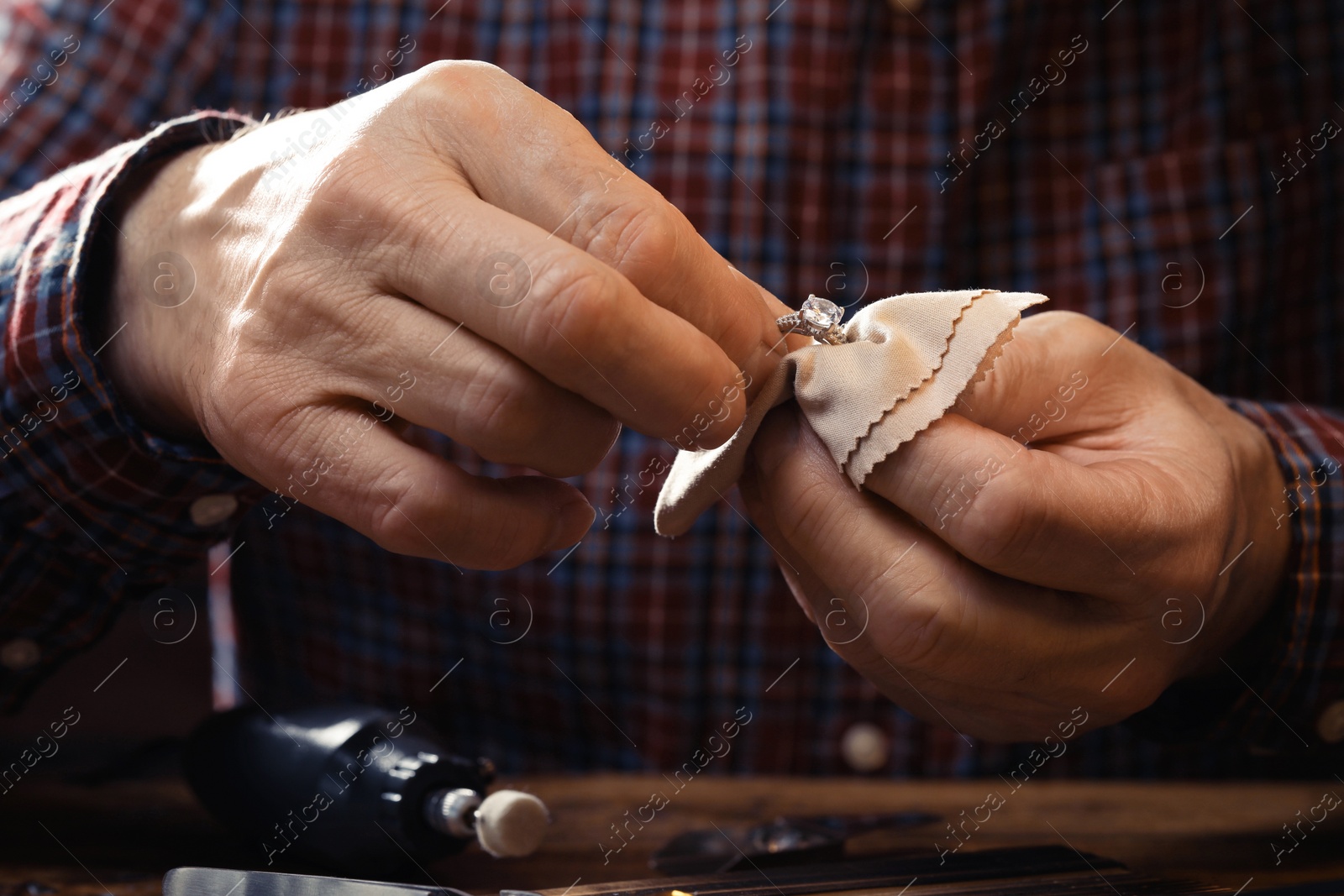 Photo of Professional jeweler working with ring at table, closeup