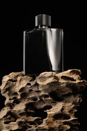 Luxury men`s perfume in bottle against black background, low angle view