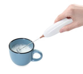 Woman whisking milk in cup with mini mixer (frother wand) isolated on white