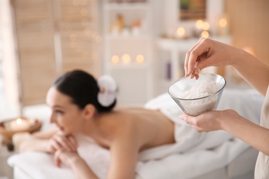 Photo of Cosmetologist holding bowl with body scrub in spa salon