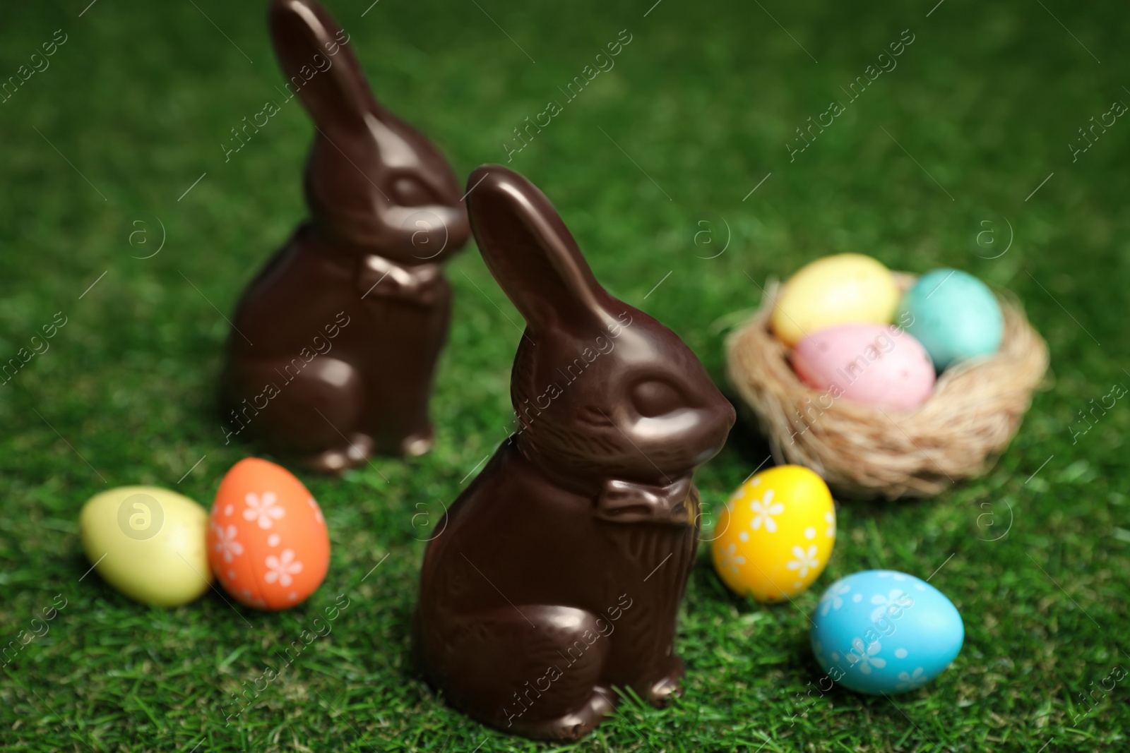 Photo of Chocolate bunnies and eggs on green grass. Easter celebration