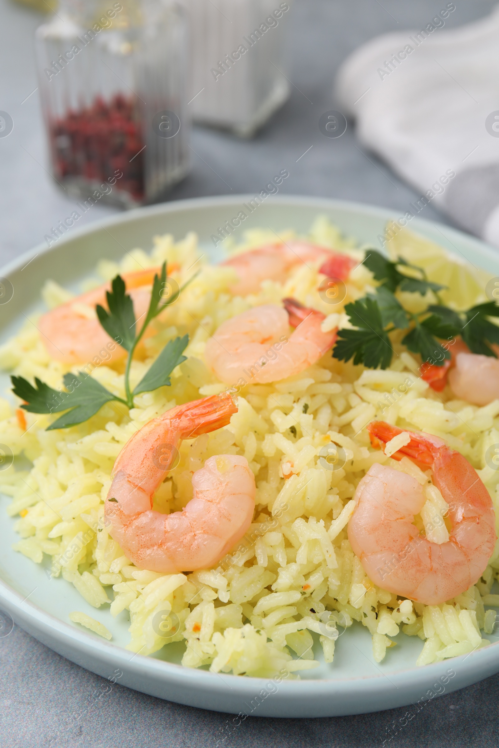 Photo of Delicious risotto with shrimps and parsley on light grey table, closeup