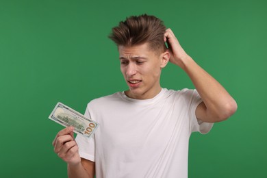 Upset man with dollar banknote on green background