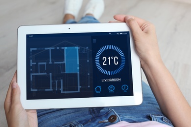 Woman using tablet to control heating system in house, closeup