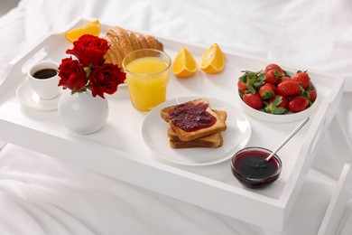 Photo of Tray with delicious breakfast on bed, closeup