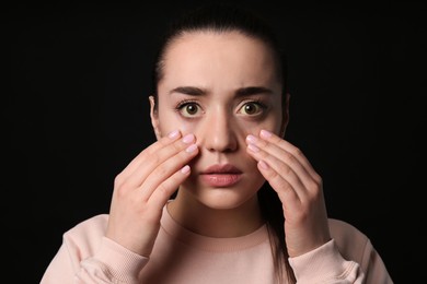 Photo of Woman checking her health condition on black background. Yellow eyes as symptom of problems with liver