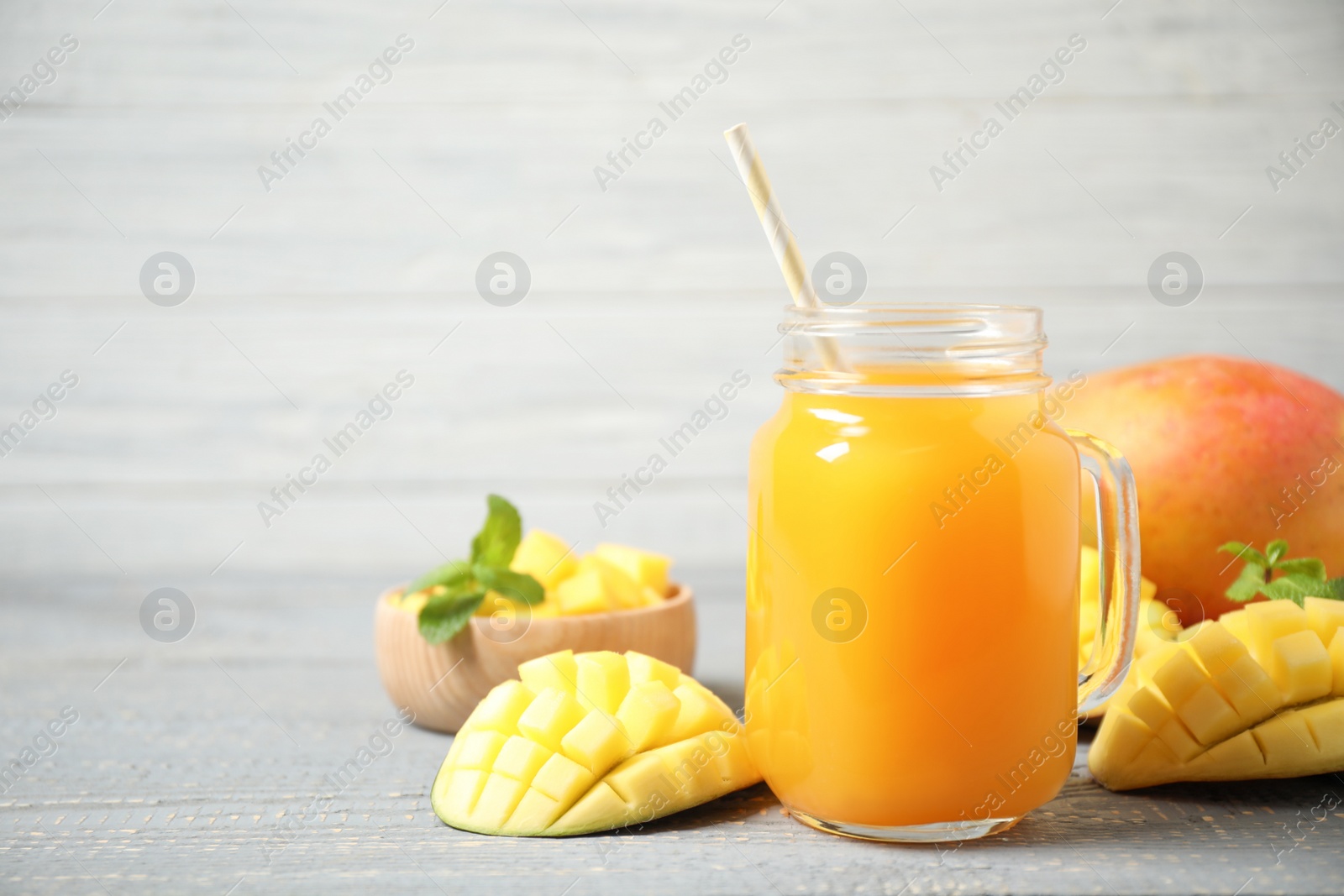 Photo of Fresh delicious mango drink on wooden table. Space for text