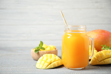 Fresh delicious mango drink on wooden table. Space for text