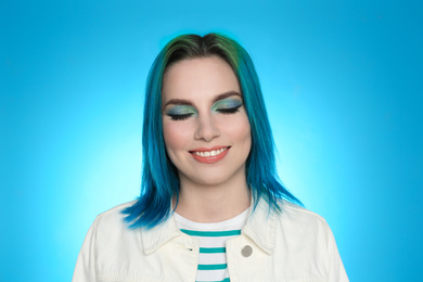 Young woman with bright dyed hair on light blue background