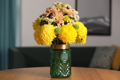 Photo of Bouquet of beautiful chrysanthemum flowers on wooden table indoors