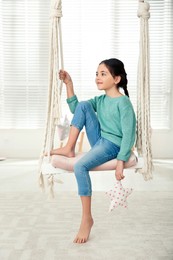 Photo of Cute little girl playing on swing at home