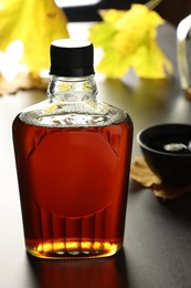 Photo of Bottle of tasty maple syrup on grey table